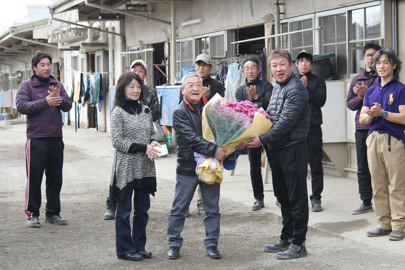 引退する星野調教師（中央）に、厩舎を代表して土田厩務員から花束を贈られた。中央左はみゑ子夫人