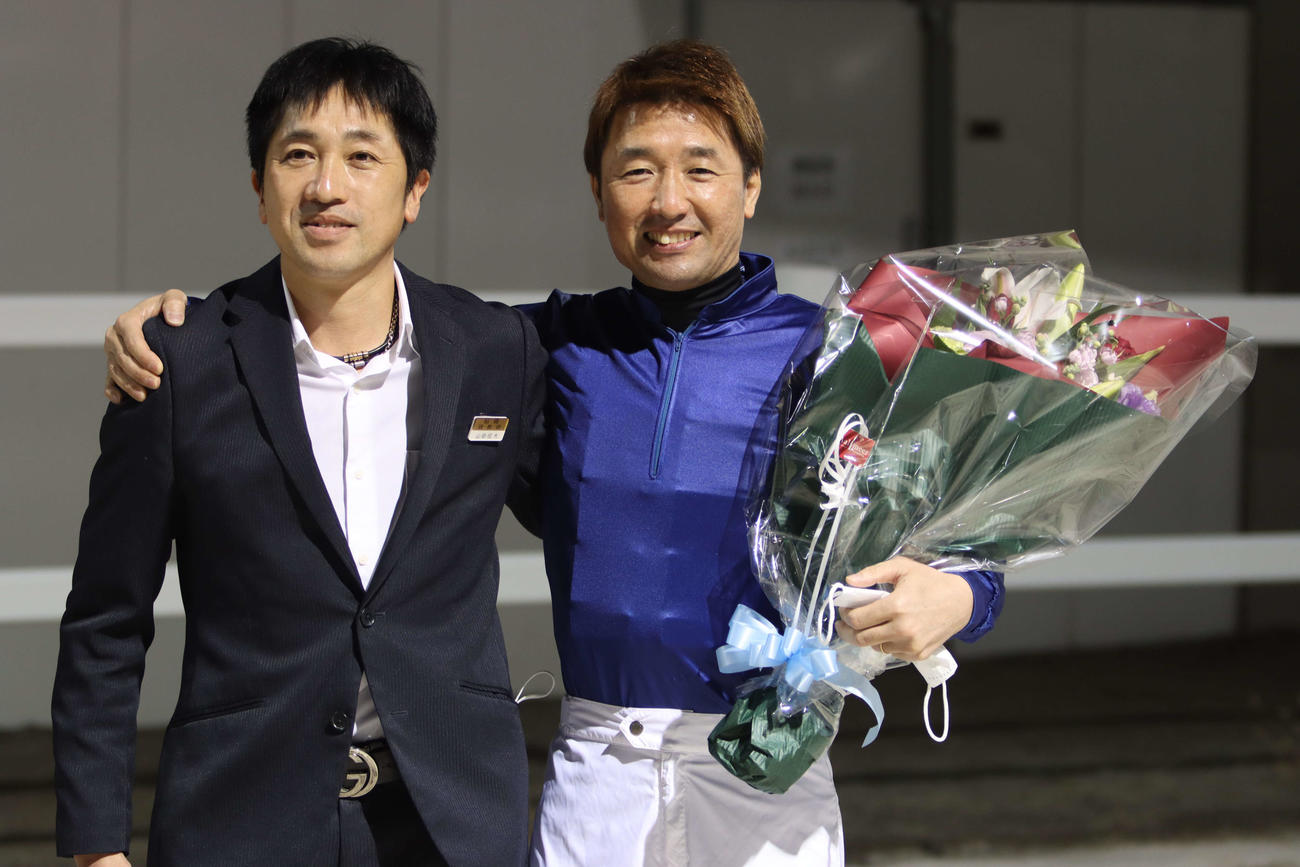 山田信大調教師（左）から花束を贈られ笑顔の酒井忍騎手