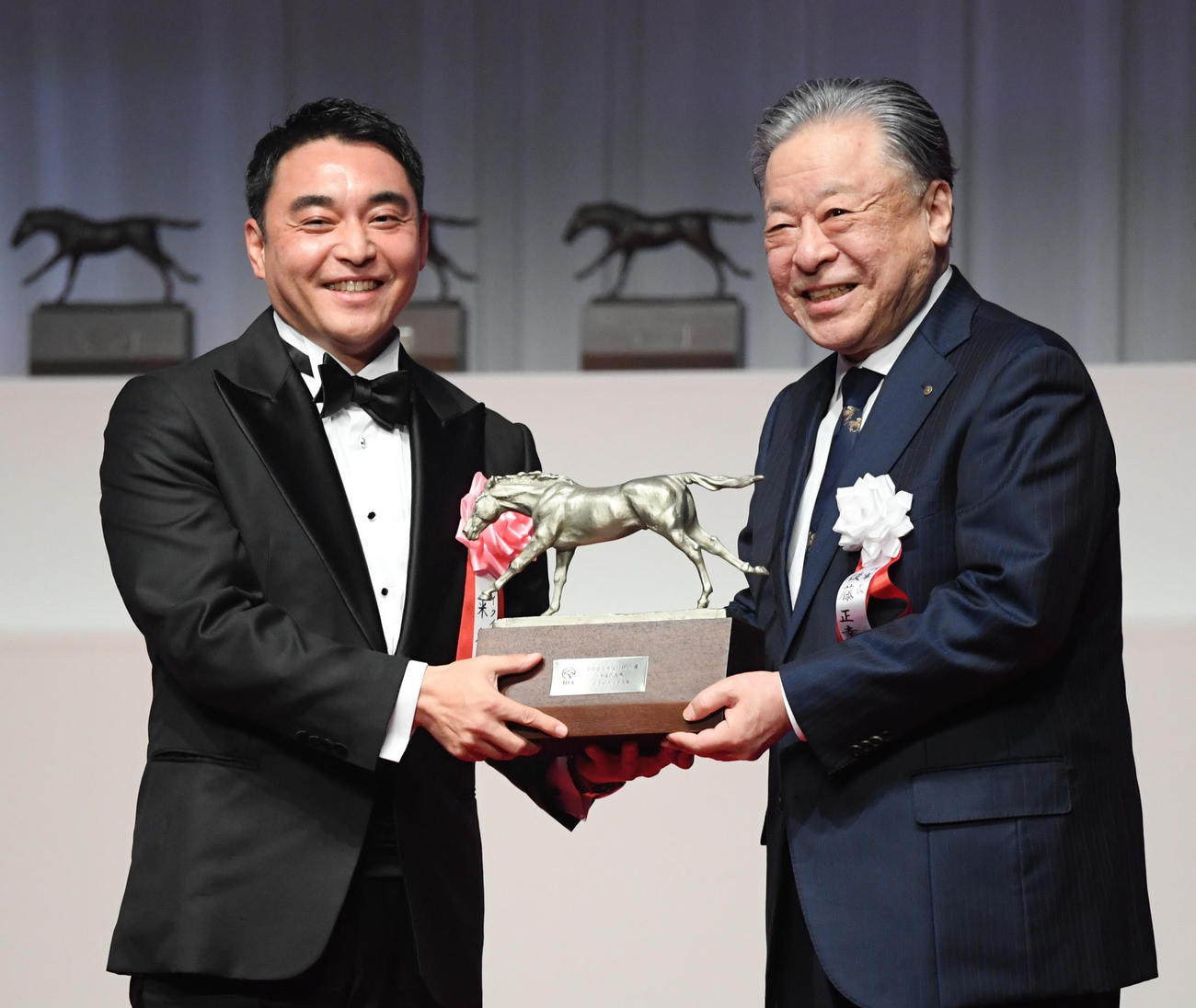 イクイノックスの米本シルクレーシング代表（左）は後藤JRA理事長からトロフィーを贈られた